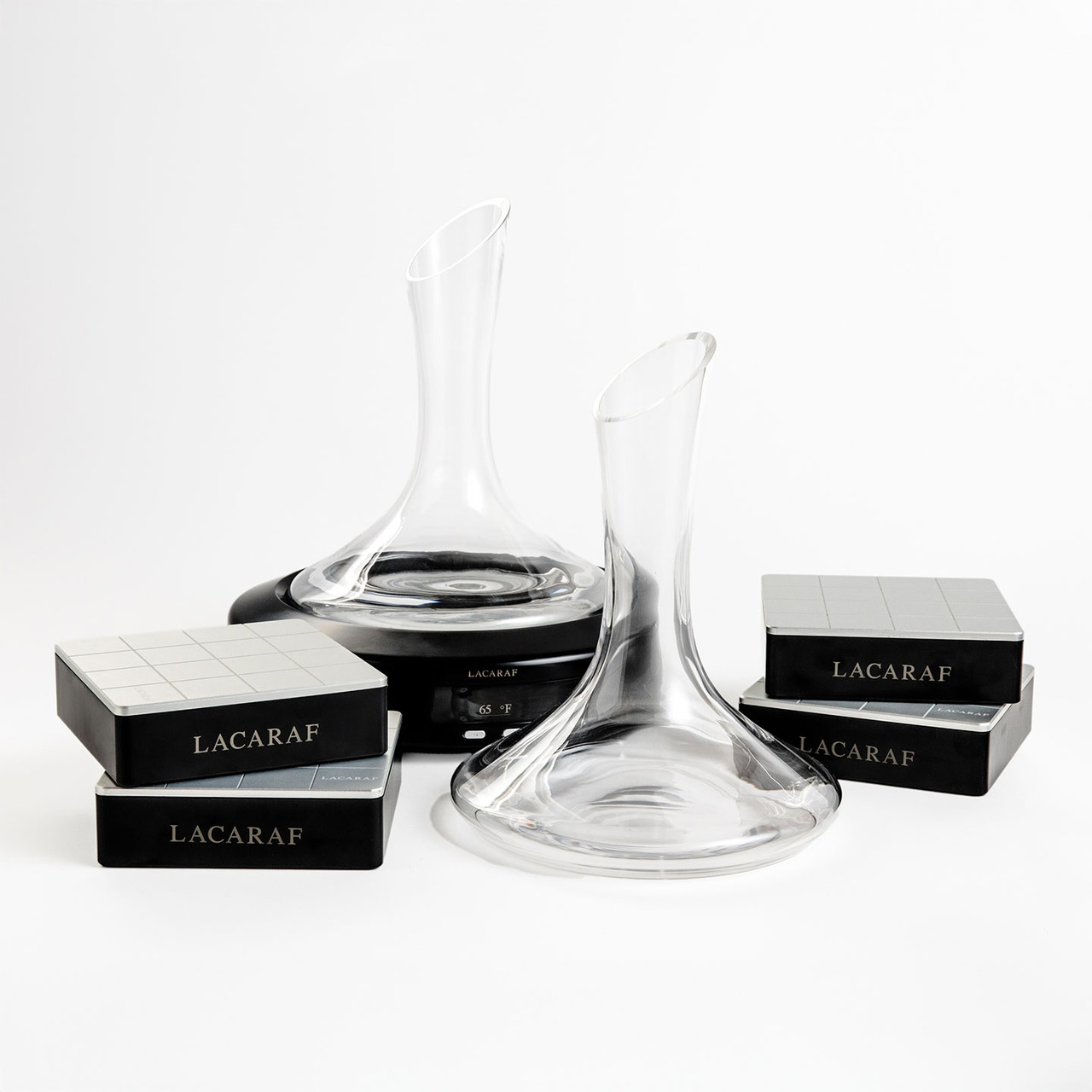two crystal decanters on black thermal bases, surrounded by four LACARAF-branded thermal capsule boxes