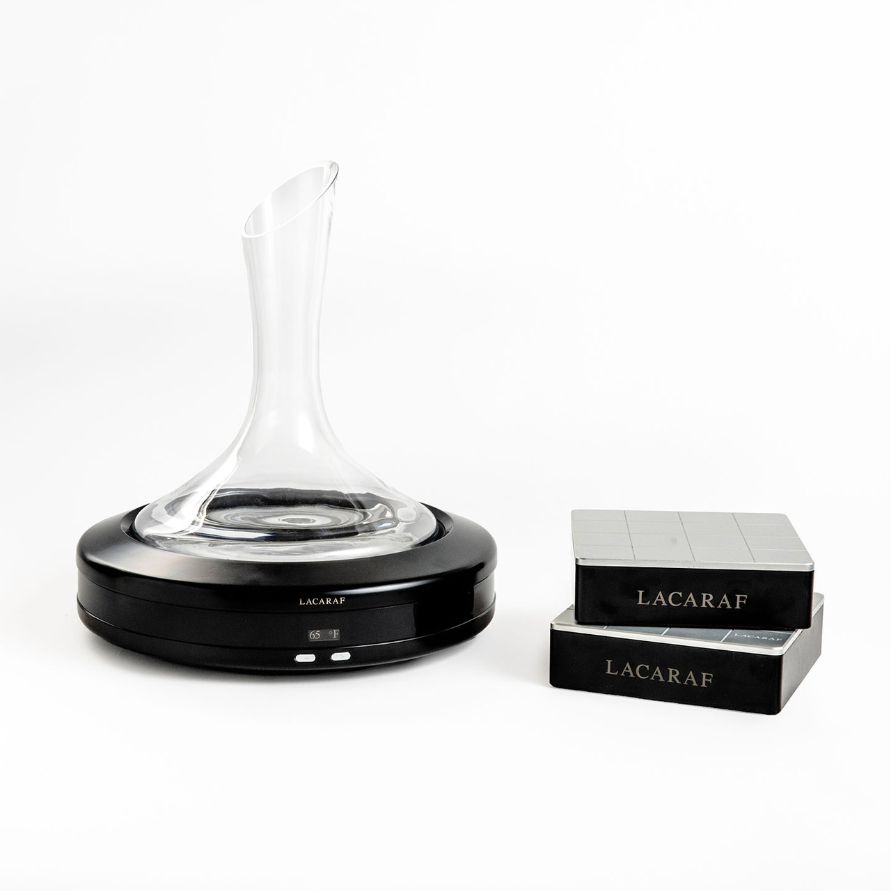 crystal decanter on its black thermal base, next to two black LACARAF-branded packaging boxes